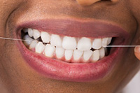 Woman flossing every day because it's important to oral heatlh
