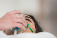Patient inhaling laughing gas through a mask, experiencing sedation and relaxation during dental treatment.